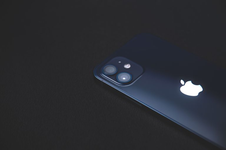 Close-up of a modern smartphone on a dark textured surface, highlighting its sleek design