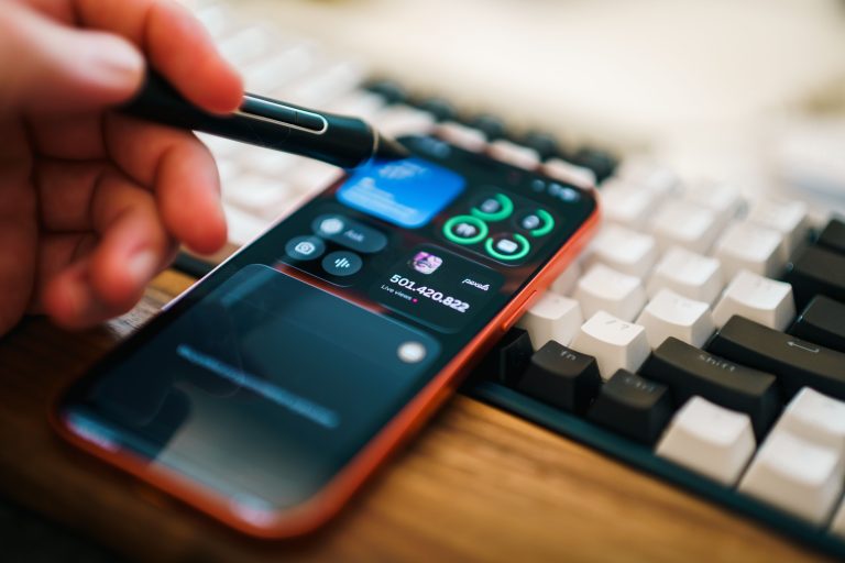 Closeup of a hand using a stylus on a smartphone, showcasing a modern digital workspace