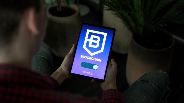 A person holds a tablet displaying a blockchain connection graphic