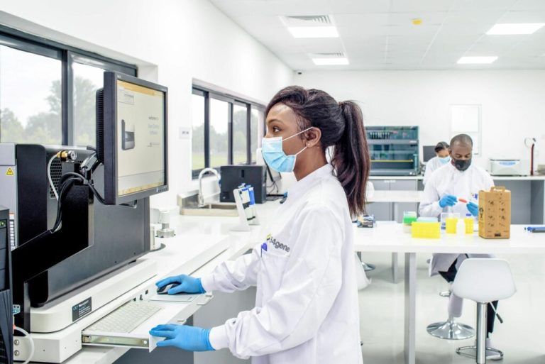 A Nigerian researcher works at laboratory equipment while colleagues work in the background