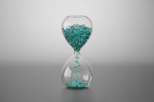Glass hourglass with tiny cubes jammed at the neck, symbolizing blockchain transaction bottlenecks.