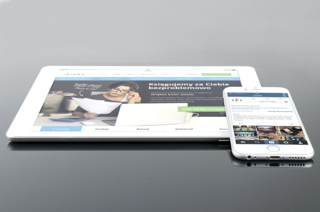 Modern tablet and smartphone displaying web content on a reflective surface, highlighting technology and connectivity