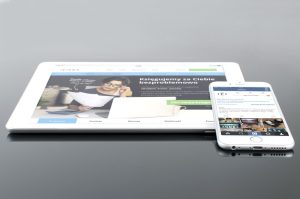 Modern tablet and smartphone displaying web content on a reflective surface, highlighting technology and connectivity