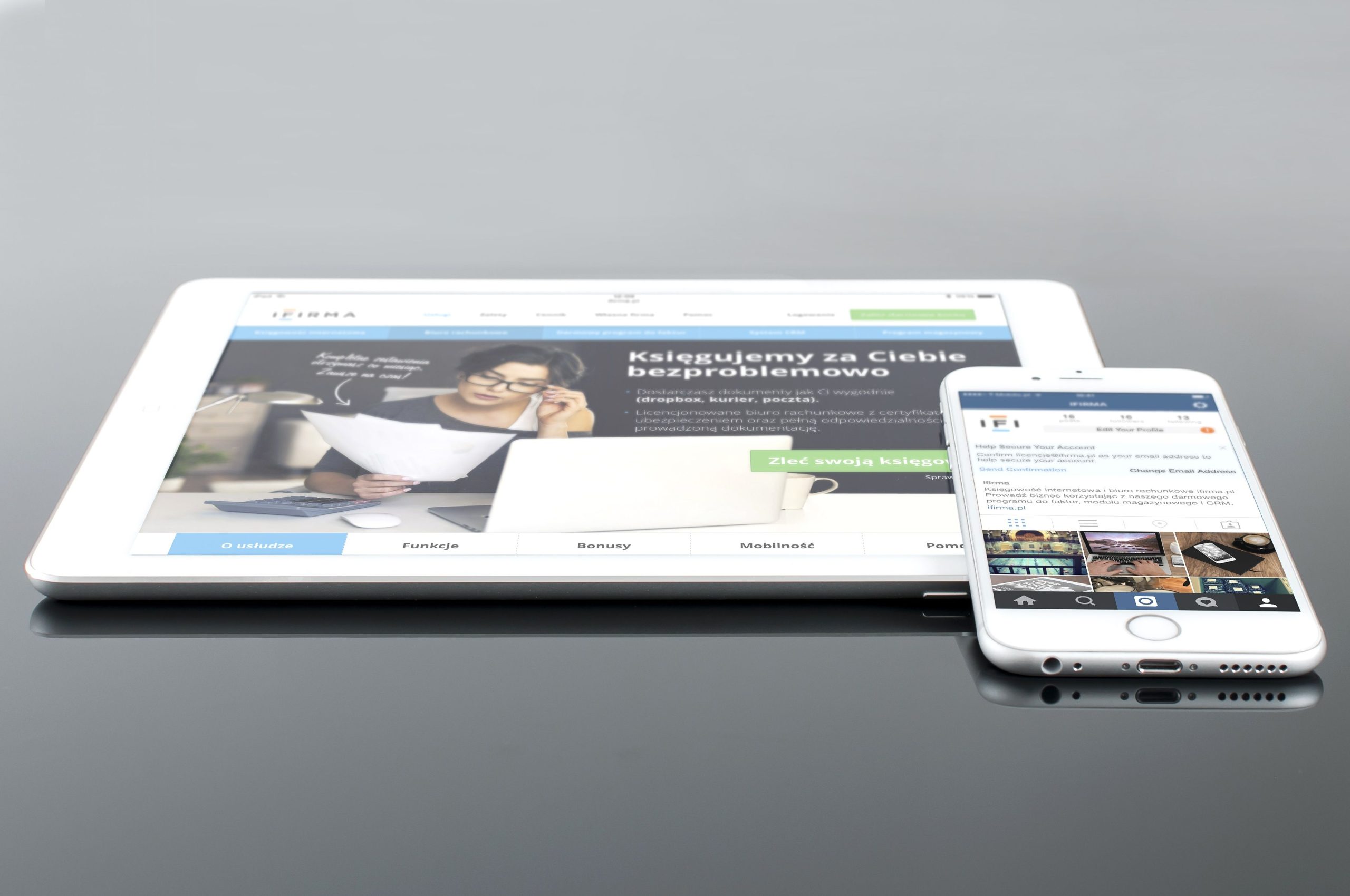 Modern tablet and smartphone displaying web content on a reflective surface, highlighting technology and connectivity