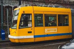 A bright yellow tram travels through the city streets, offering public transportation to passengers