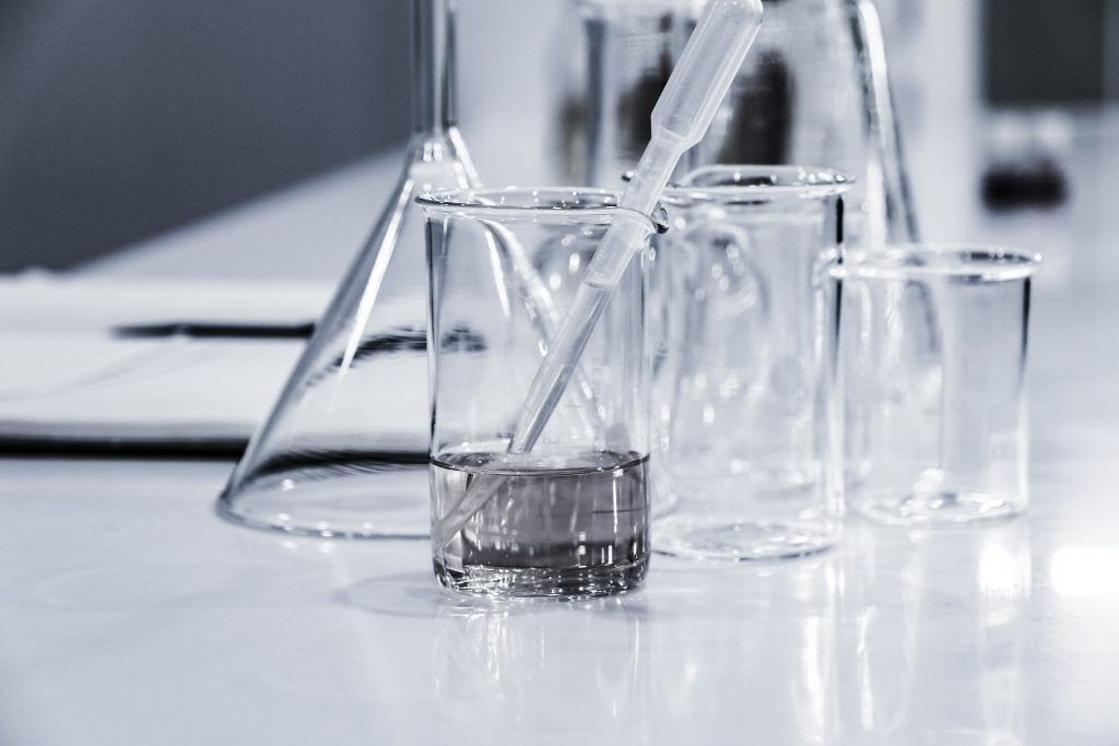 Clear laboratory glassware and a pipette on a workbench