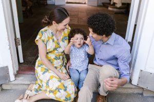 A joyous family moment captured as parents sit with their cheerful child on a doorstep