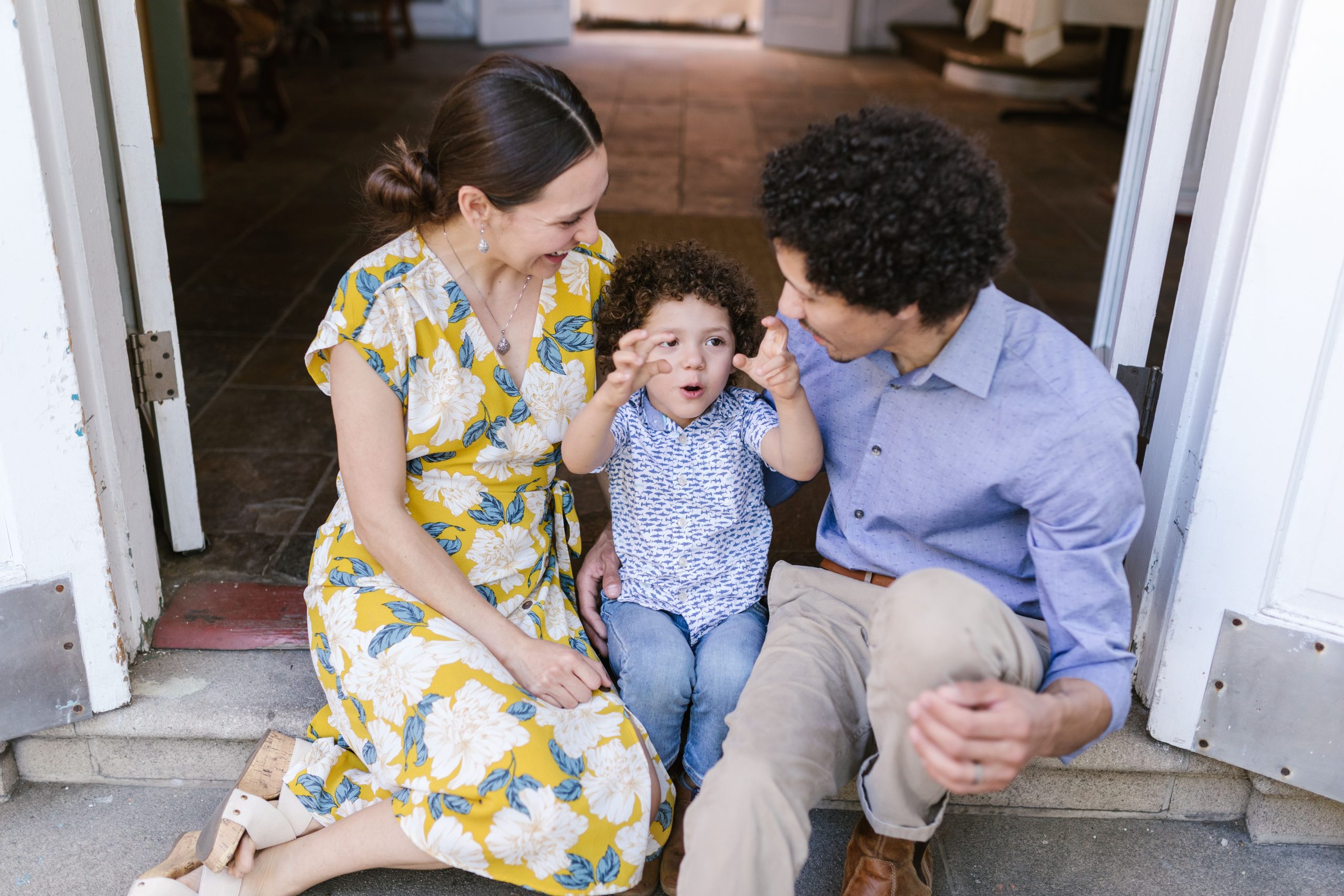 A joyous family moment captured as parents sit with their cheerful child on a doorstep