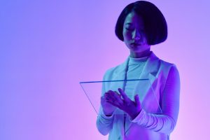 A woman holding a transparent panel under purple and blue studio lighting